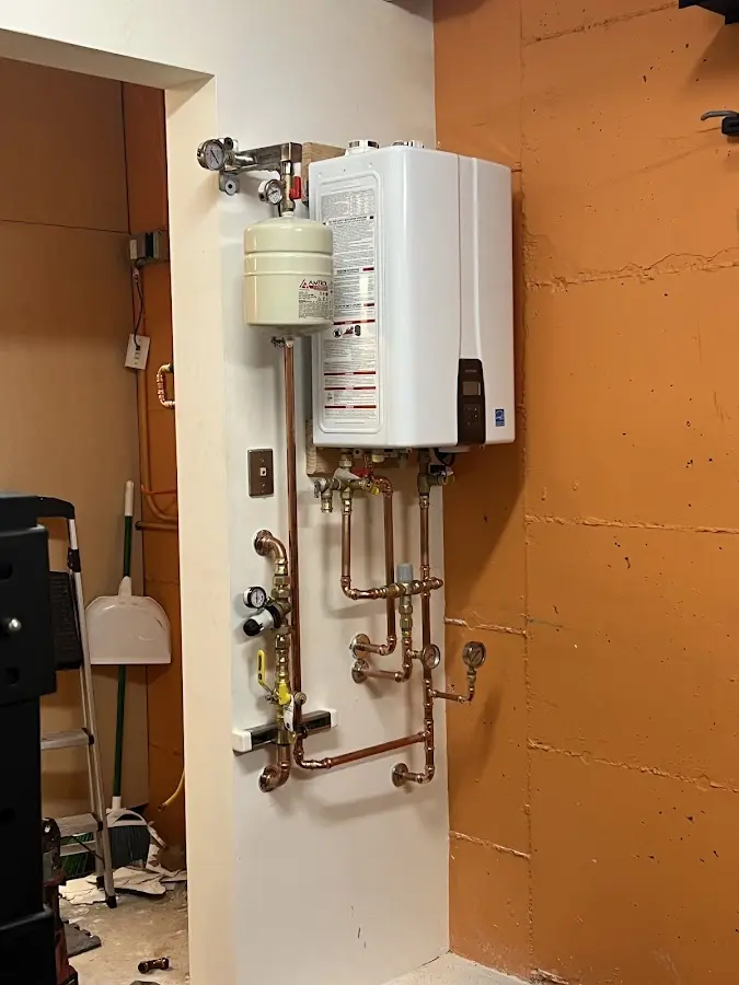Plumbing technician inspecting water heater connections in Lyman